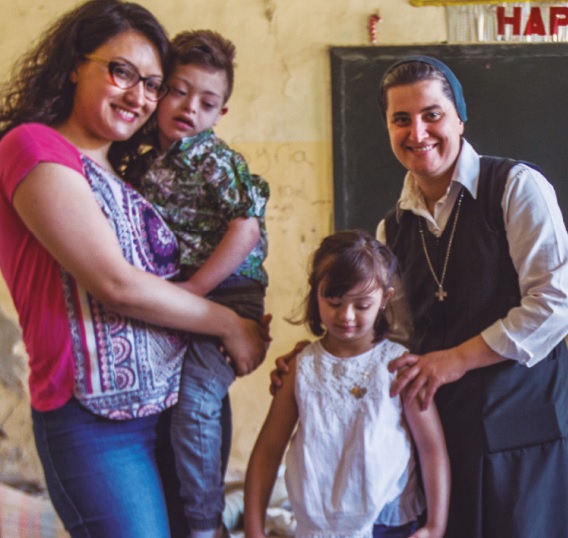 Hna. Samia Syiej con una familia en una de las casas afectadas por las bombas en Homs, Siria. (ACN).