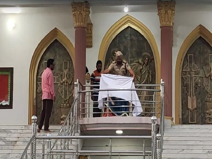 Un policía tapa la imagen de la Virgen María atacada. (AsiaNews)
