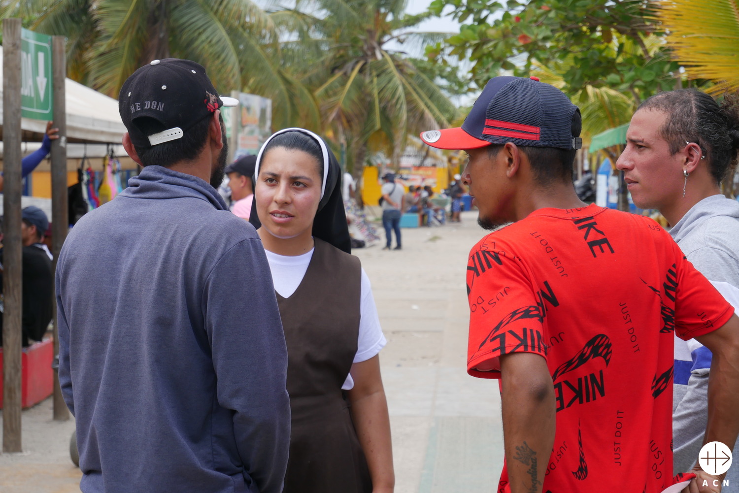 La hermana Deisy, religiosa franciscana de María Inmaculada, conversa con emigrantes en la playa de Necoclí. (ACN)