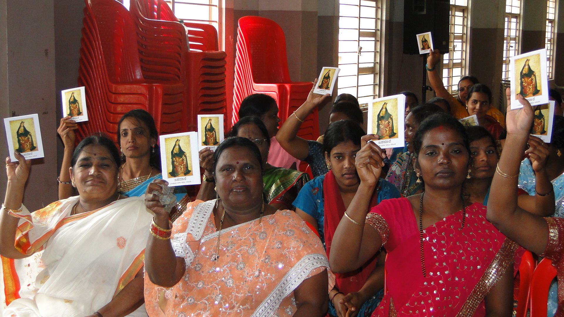 Mujeres indias enseñan un cuaderno para rezar el rosario. (ACN)
