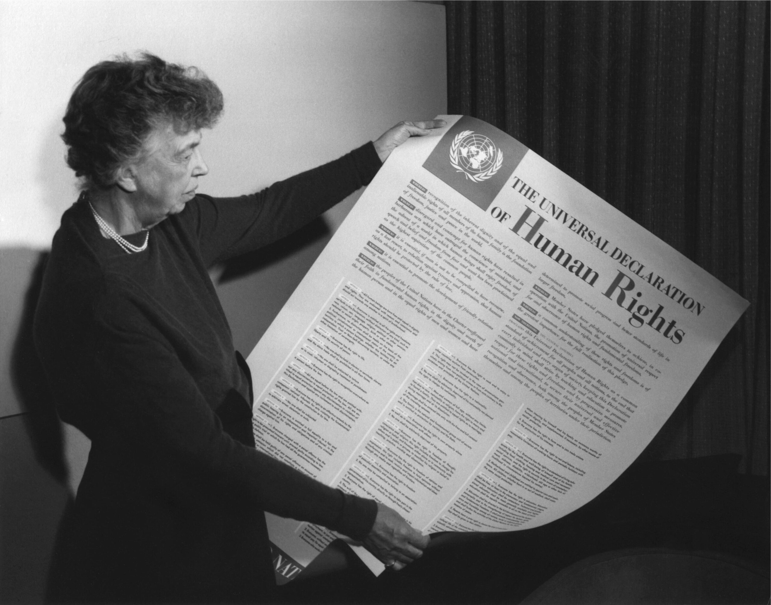 Eleanor Roosevelt sosteniendo un cartel de la Declaración Universal de Derechos Humanos (en inglés), Lake Success, Nueva York. Noviembre de 1949.