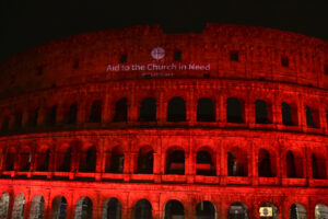 Coliseo de Roma iluminado de rojo con el logo de ACN