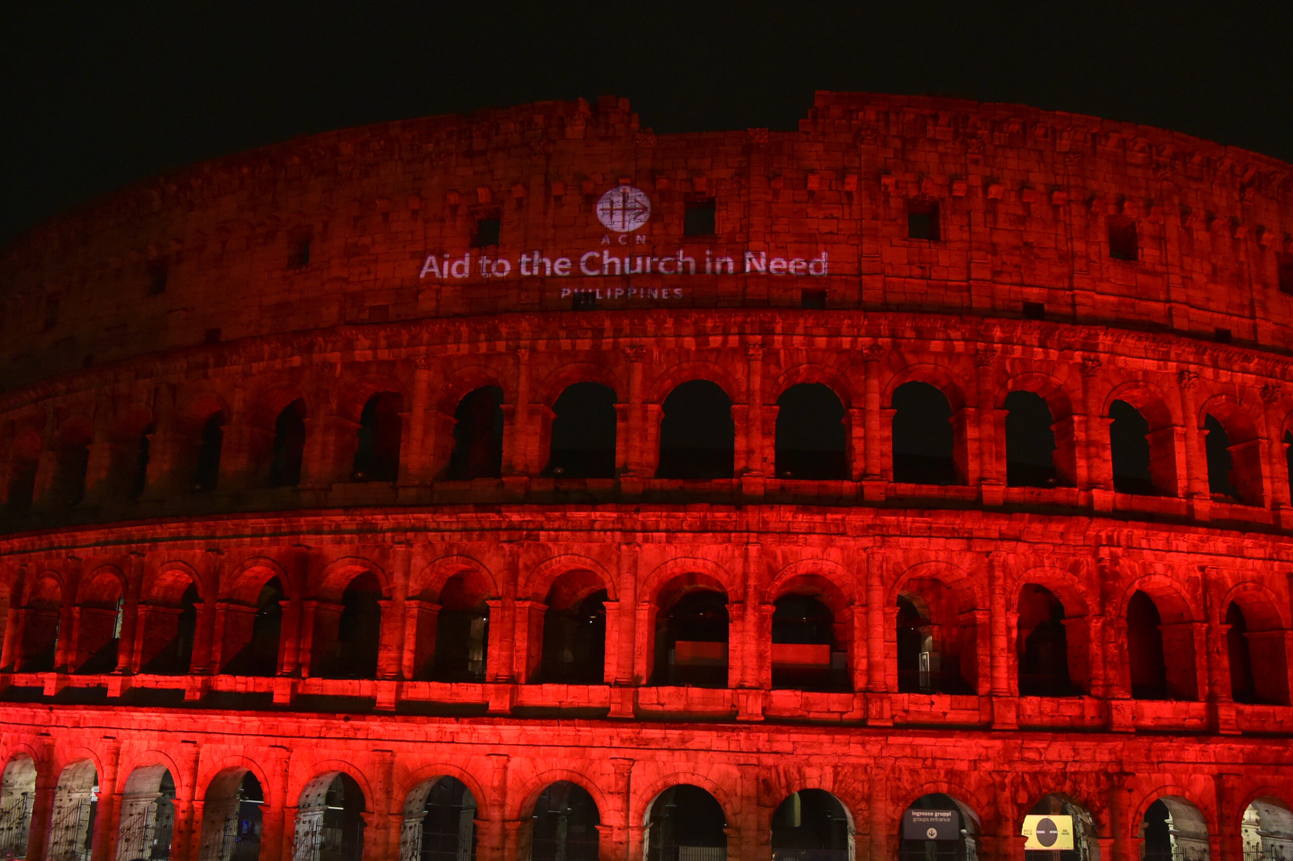 Coliseo de Roma iluminado de rojo con el logo de ACN