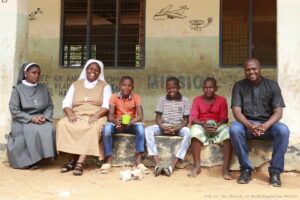 Un sacerdote, monjas y chicos en frente de una escuela en Tarasaa (Kenia)