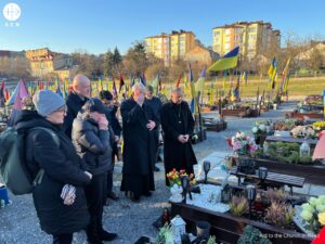 Sacerdotes y fieles rezan ante una tumba en el cementerio de Lviv (Ucrania)