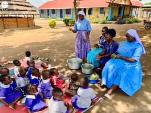 Dos monjas dan catequesis a un grupo de niños en el campo de refugiados de Palabek (Uganda)