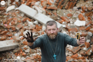El padre Victor, sacerdote ucraniano, encuentra una estampa de la Virgen María entre las ruinas de un edificio destruido. © Ismael Martínez Sánchez / ACN