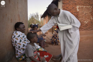 Un catequista reza por un niño durante una reunión con fieles
