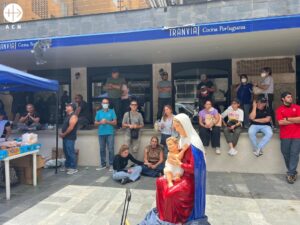 Personas en la calle en Caracas, rezando juntas en torno a una imagen de la Virgen y junto a un puesto de ayuda de la Iglesia católica
